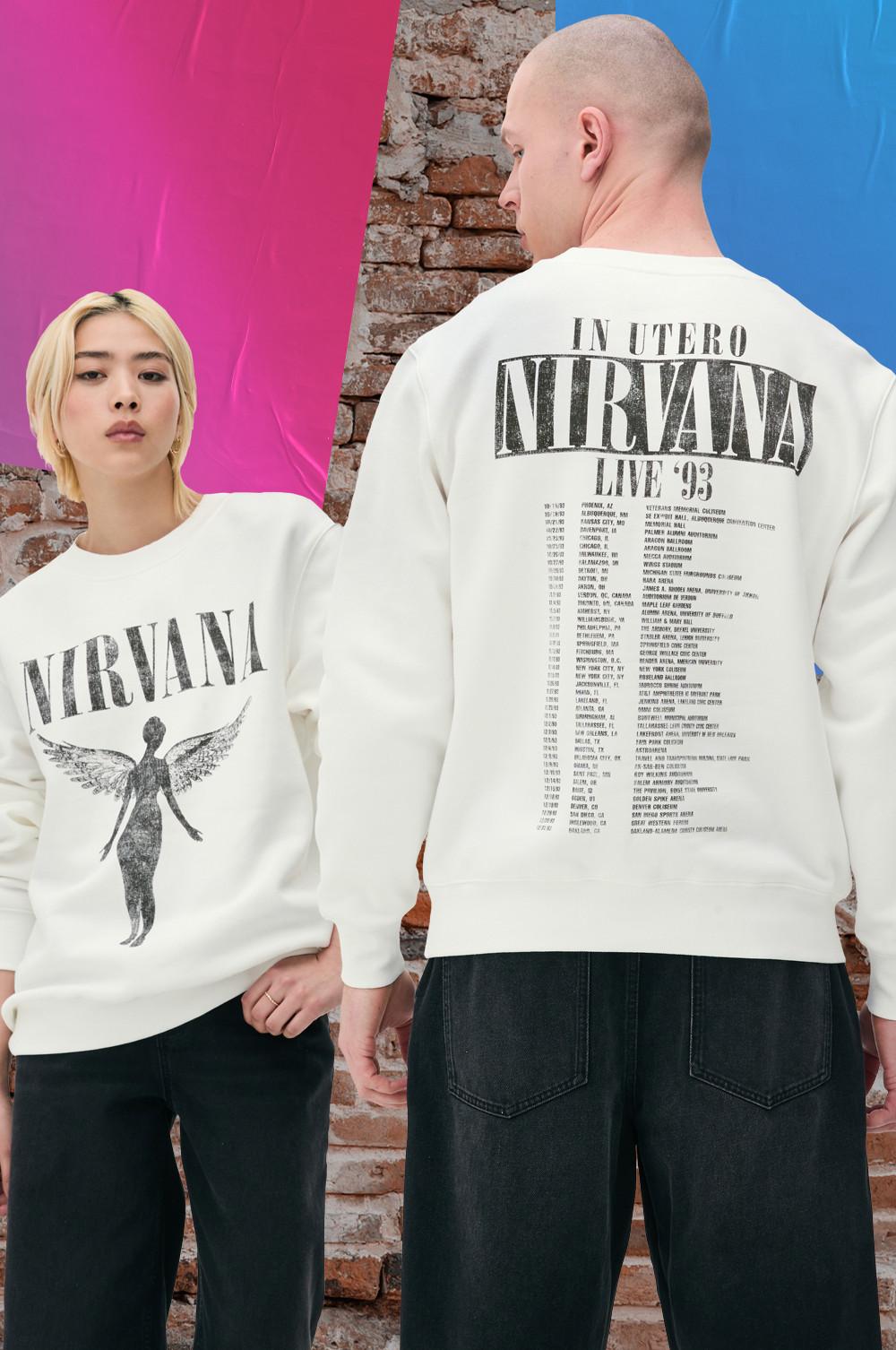 Two people wearing white Nirvana sweatshirts. Front features angel graphic, back lists tour dates.