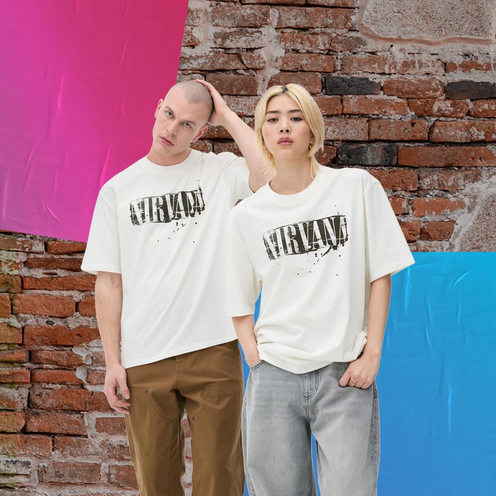 Two model wearing white Nirvana T-shirts, standing against a brick wall.