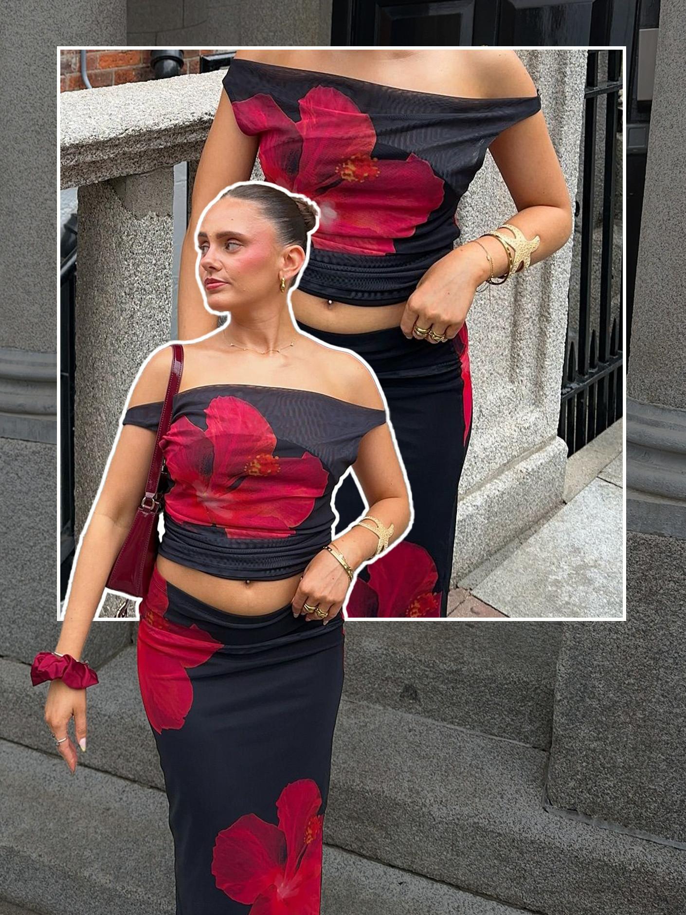 Black off-shoulder crop top and skirt set with bold red hibiscus flower print, accessorised with gold bracelets.