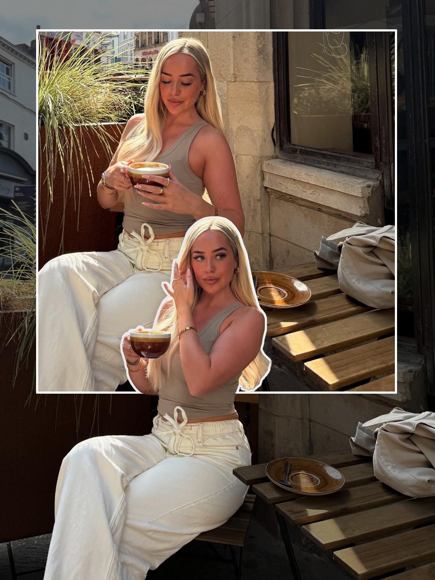 Person in beige tank top and white trousers enjoying coffee at an outdoor café table.
