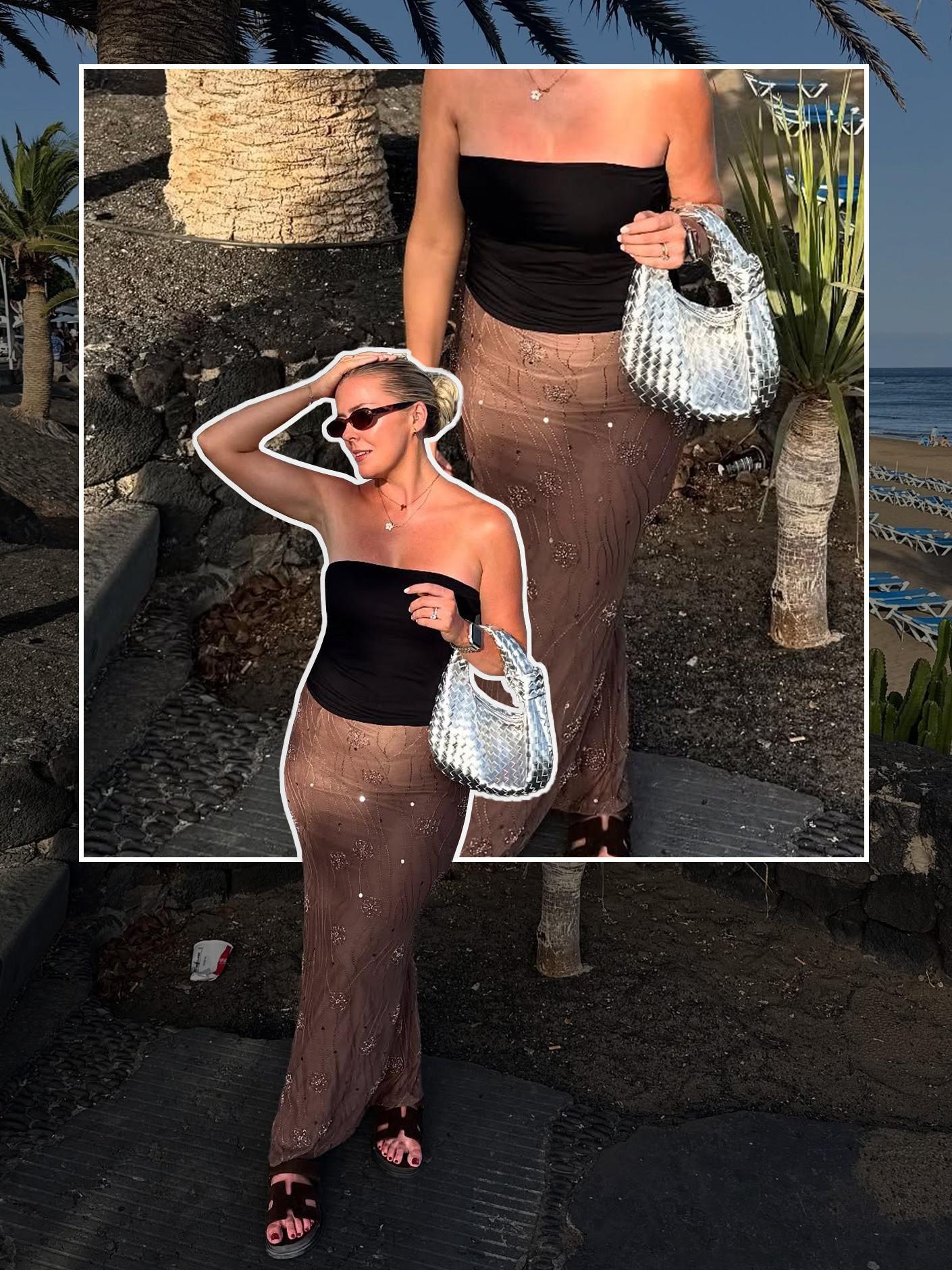 Person wearing black tube top with brown embellished skirt holding a metallic woven handbag at a beach resort.