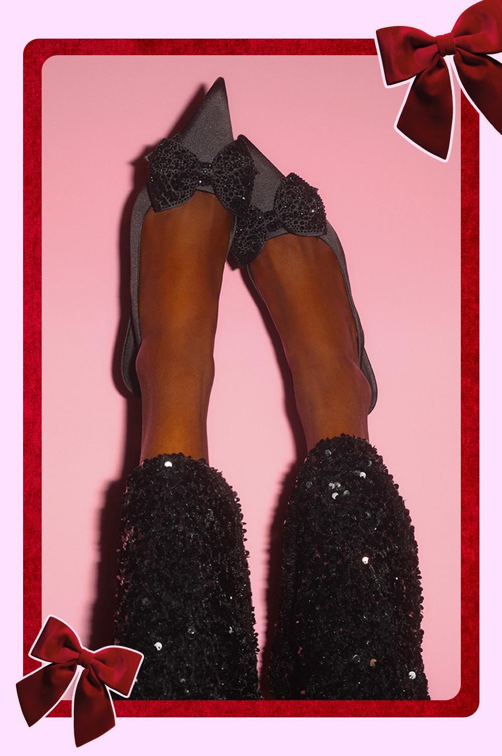 Ballerine grigie con fiocchi con paillettes neri abbinate a leggings neri glitterati in una cornice rossa festosa.