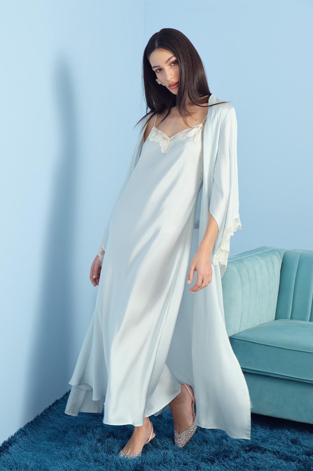 Model wearing white maxi satin gown and a satin robe with feather cuffs.
