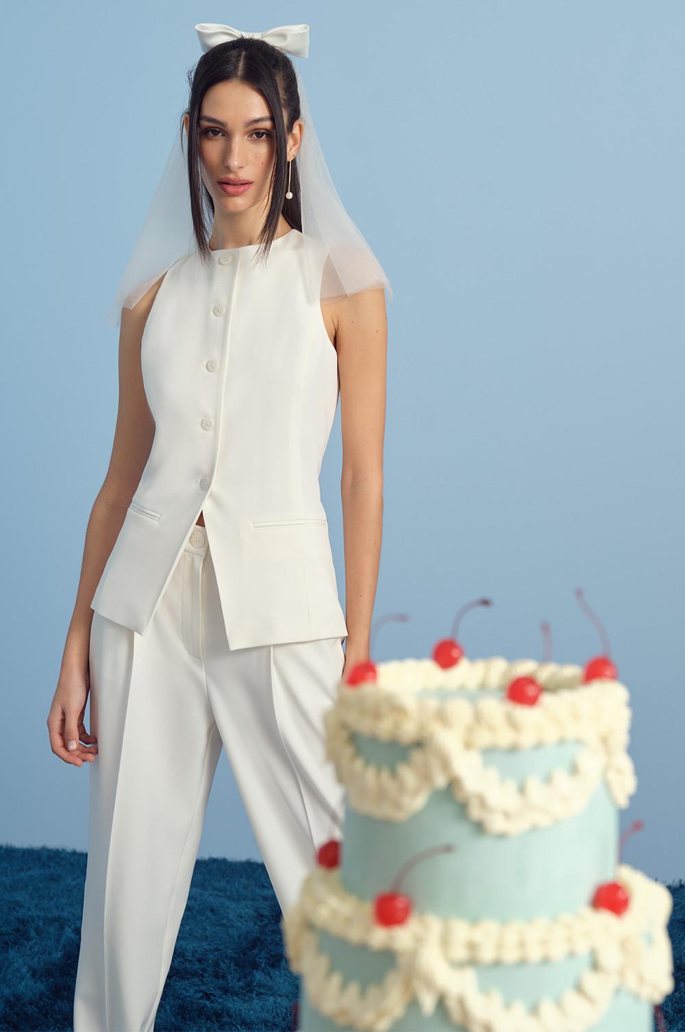 Model wearing a white vest, pants and veil with bow