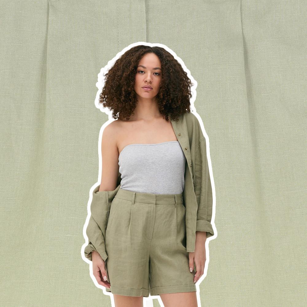 Grey strapless top paired with sage green shorts and matching open jacket against a linen background.