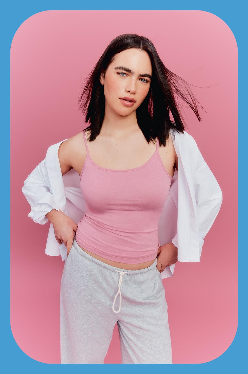 Model wearing pink cami top, white jacket and grey joggers
