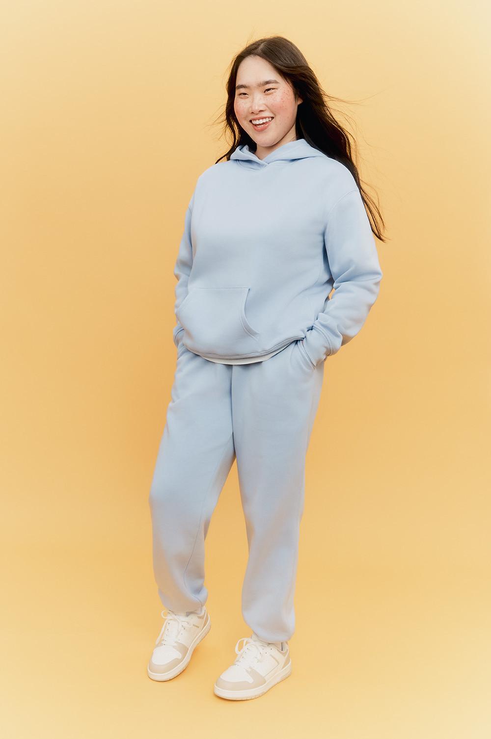 Model wearing grey joggers and hoodie with white trainers