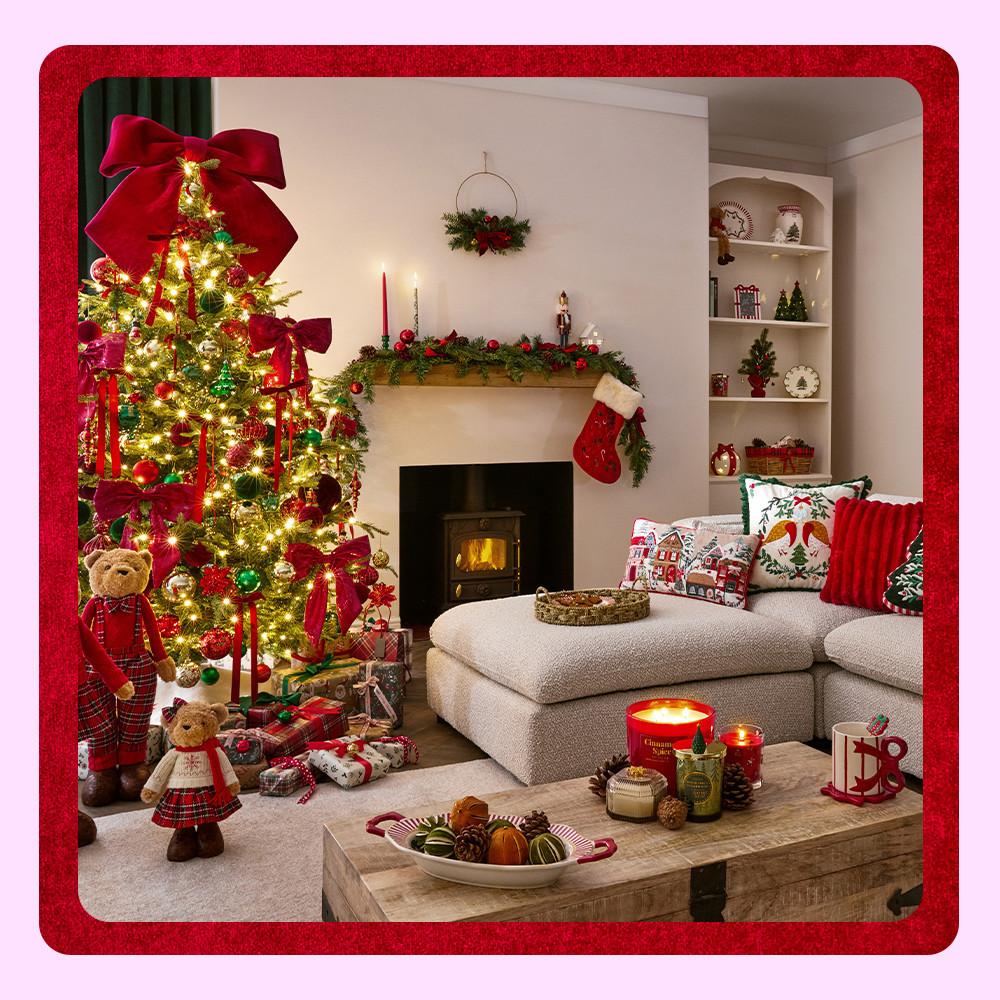 Festive living room with decorated Christmas tree, stockings on fireplace mantel, and holiday cushions on sofa.