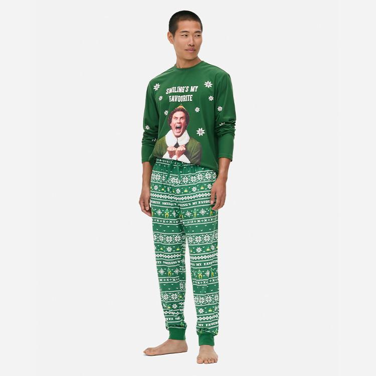 Person wearing green Christmas pyjama set with "SMILING'S MY FAVOURITE" text and festive pattern trousers.