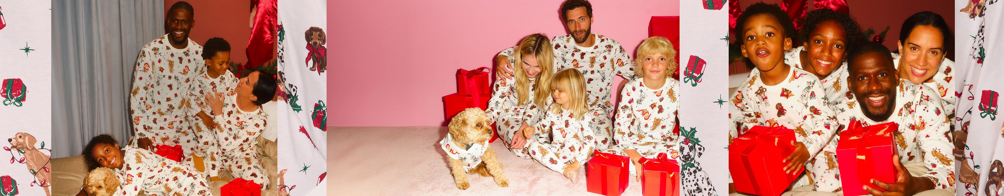 A group wearing matching Christmas pyjamas with children holding red gift boxes and a dog.