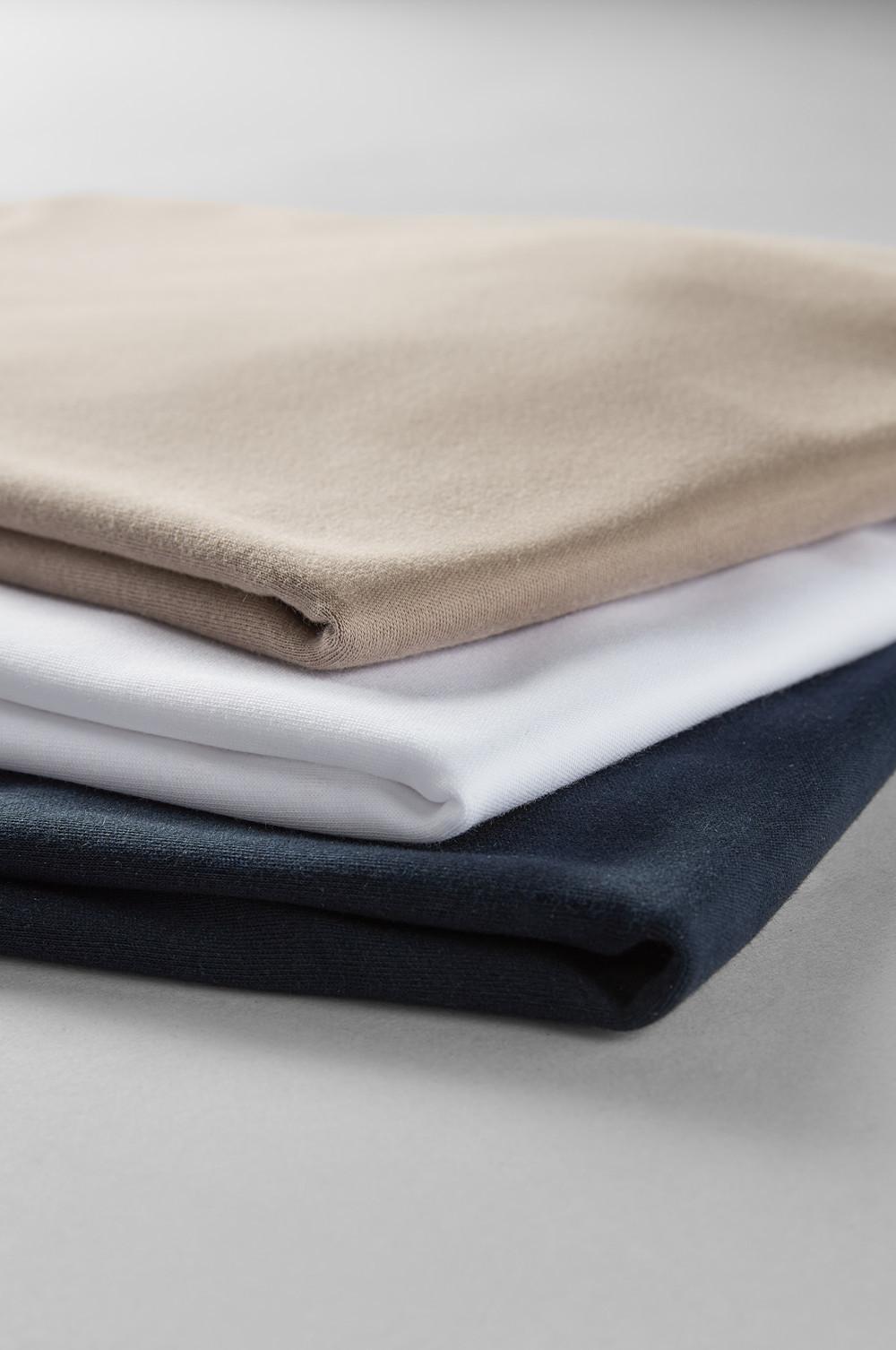 Three folded sweatshirts in beige, white and navy