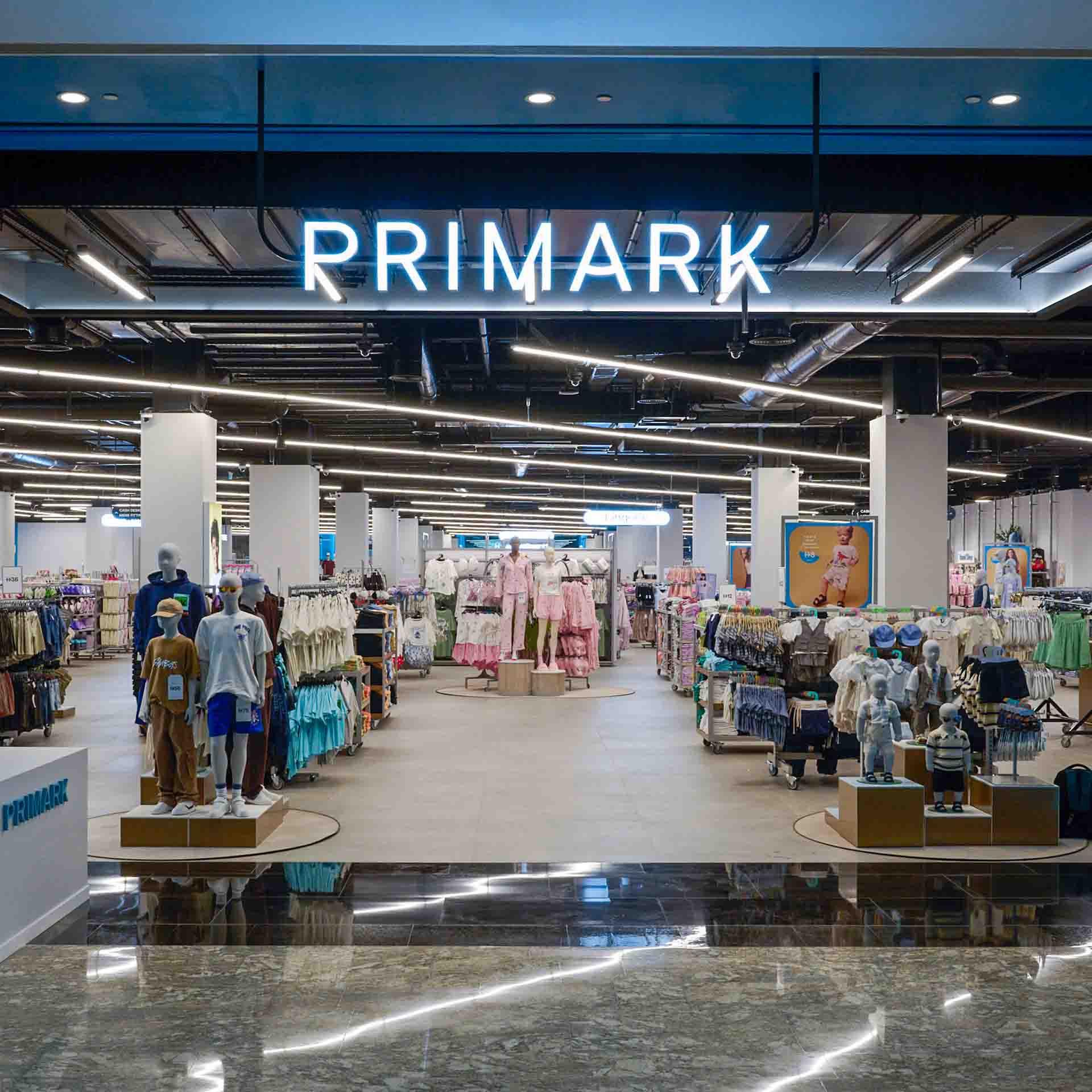 Interior of a Primark store with neatly arranged clothing displays.