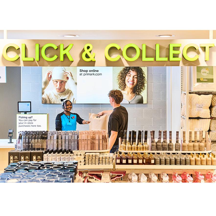 A Primark employee at the Click & Collect till, handing over an order to a customer.
