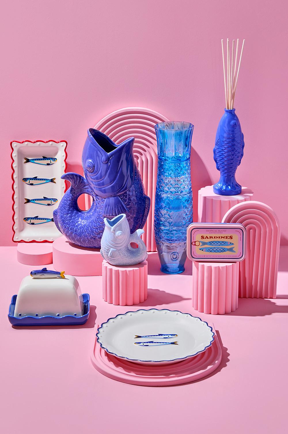 Collezione di ceramiche e oggetti in vetro a tema ittico, tra cui piatti, vasi e una scatola di sardine.