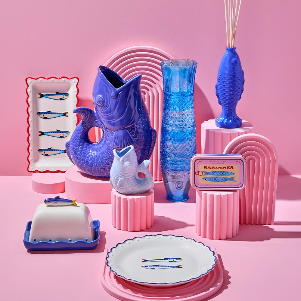 Collection of fish-themed ceramics and glassware, including plates, vases, and a sardine tin.