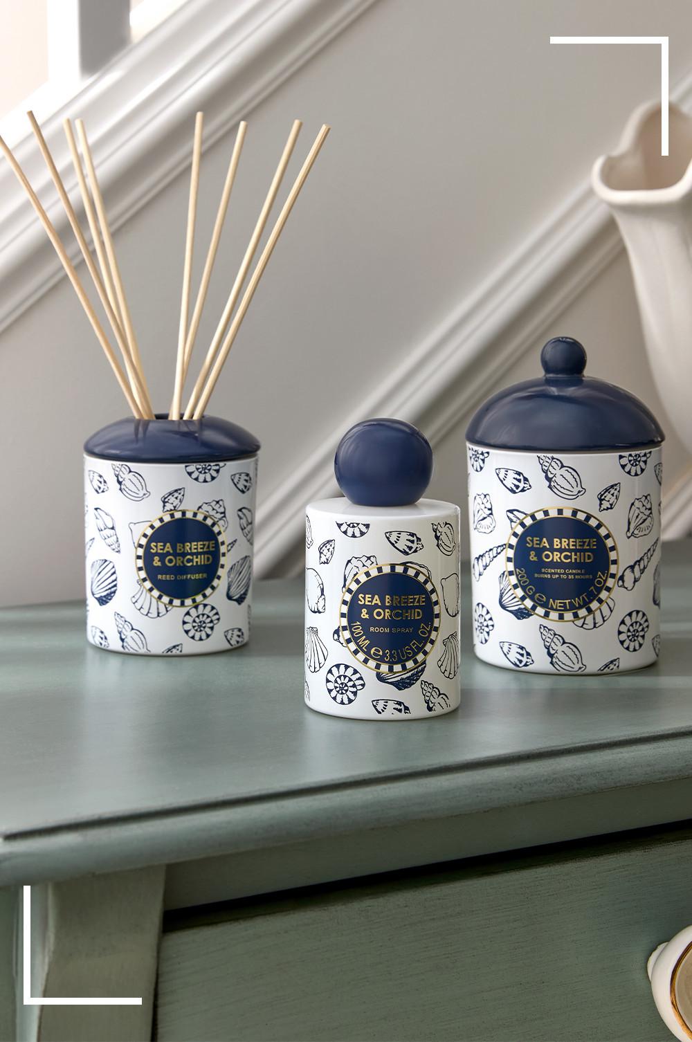 Sea Breeze & Orchid Raumduft-Kollektion mit Diffusor, inklusive Stäbchen, Raumspray und Duftkerze in blauen und weißen Behältern mit Muschel-Motiven.
