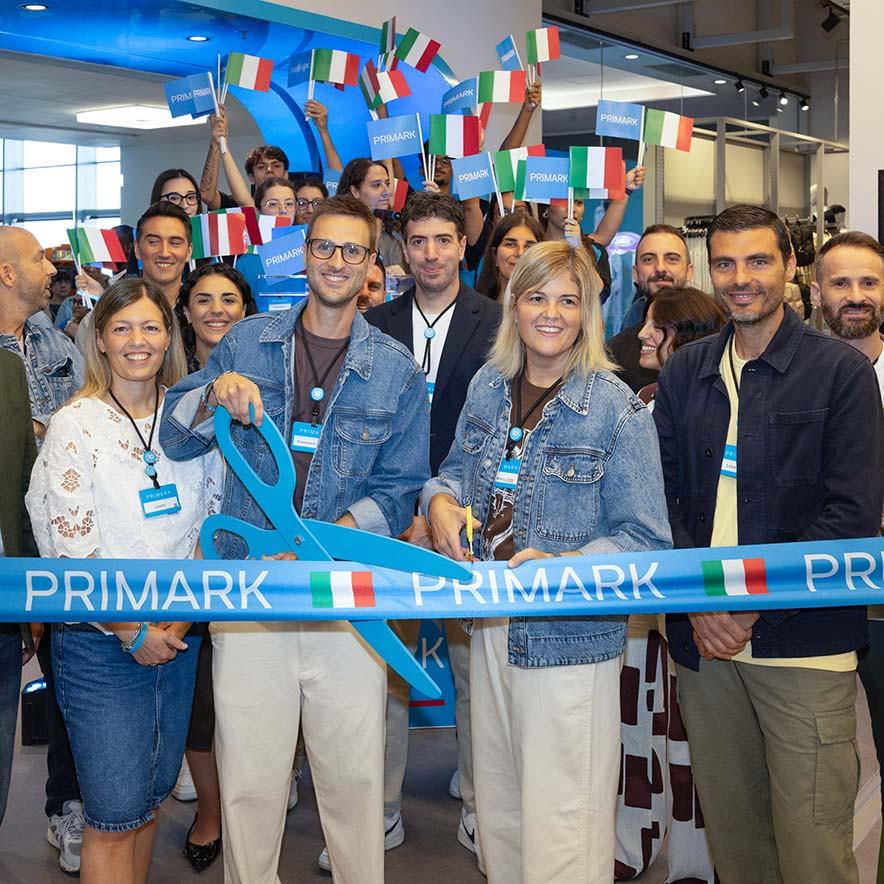 A group of people in a store cut a blue Primark ribbon with large scissors.