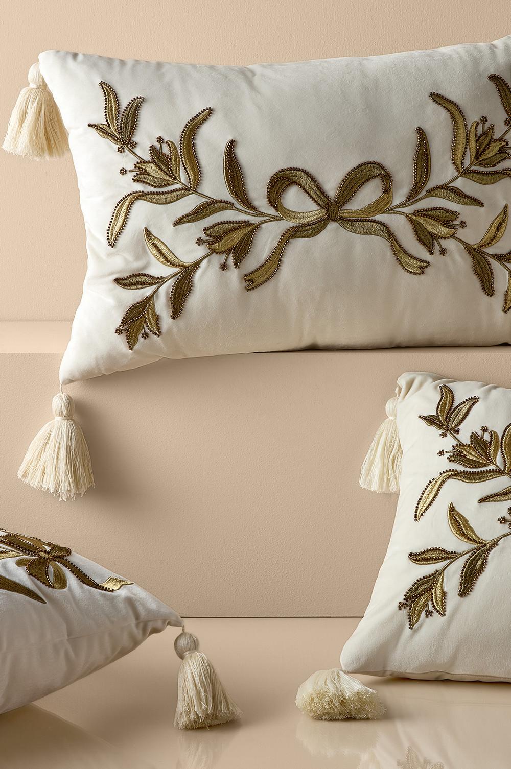 White decorative cushions with gold embroidered floral design and cream tassels at corners.