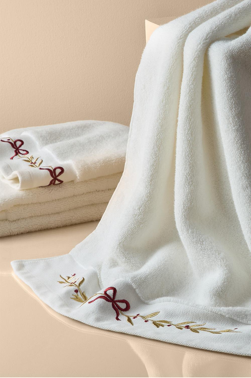 Soft white towels with festive red bow and green leaf embroidery detail along the edges.