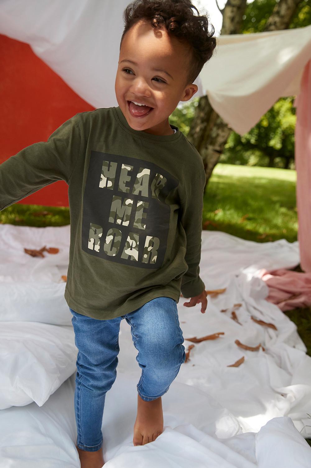 bambino con maglia verde e jeans