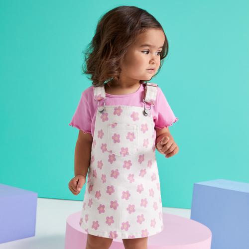 Child in pink T-shirt and floral overall dress
