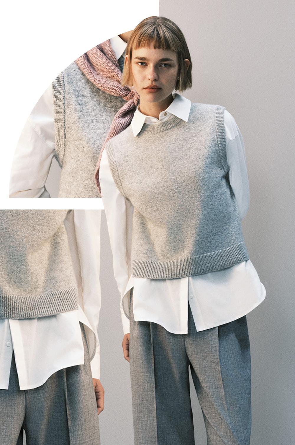 Grey knitted sweater vest layered over white button-up shirt with grey pants, creating a stylish layered look.
