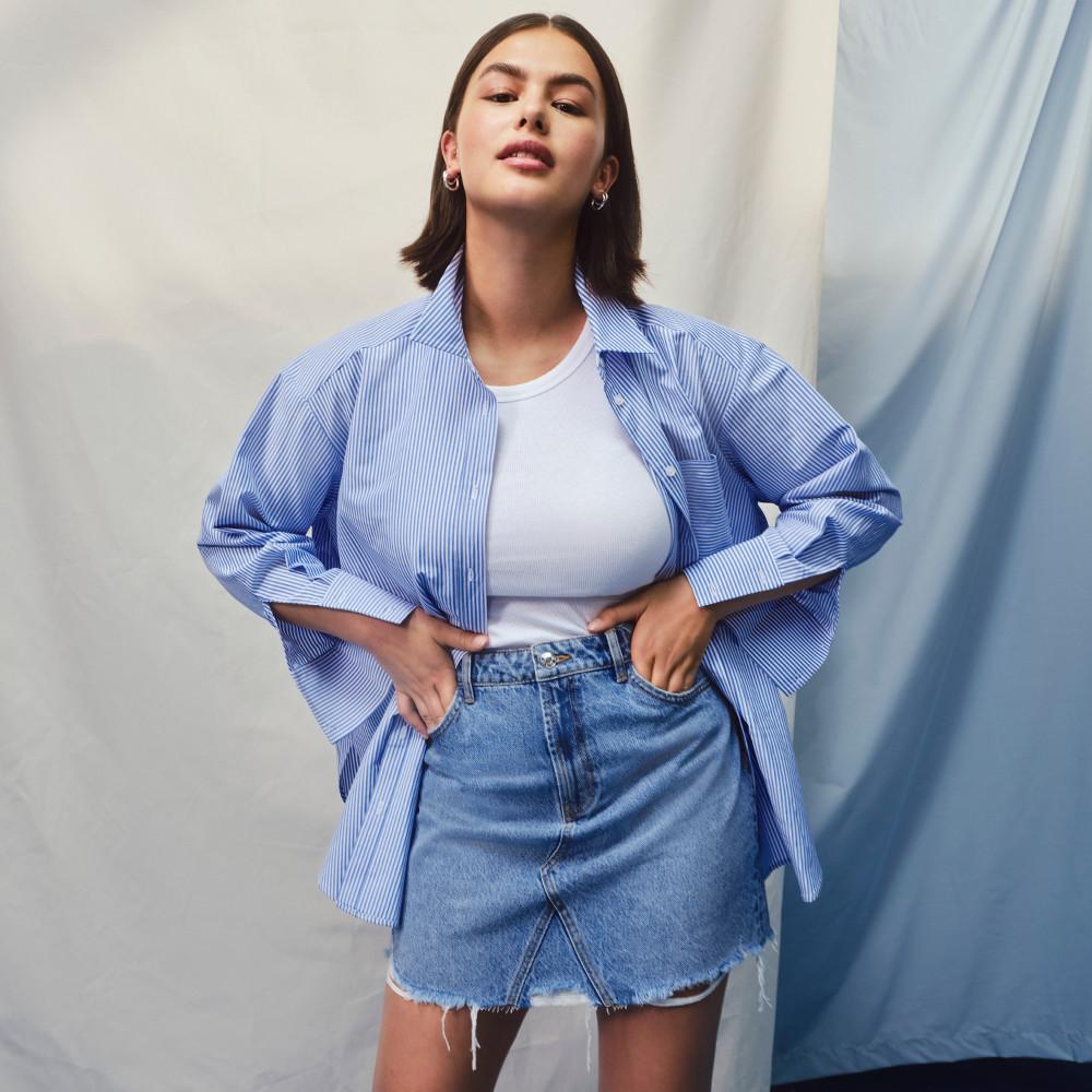 Model wearing shirt and denim mini skirt