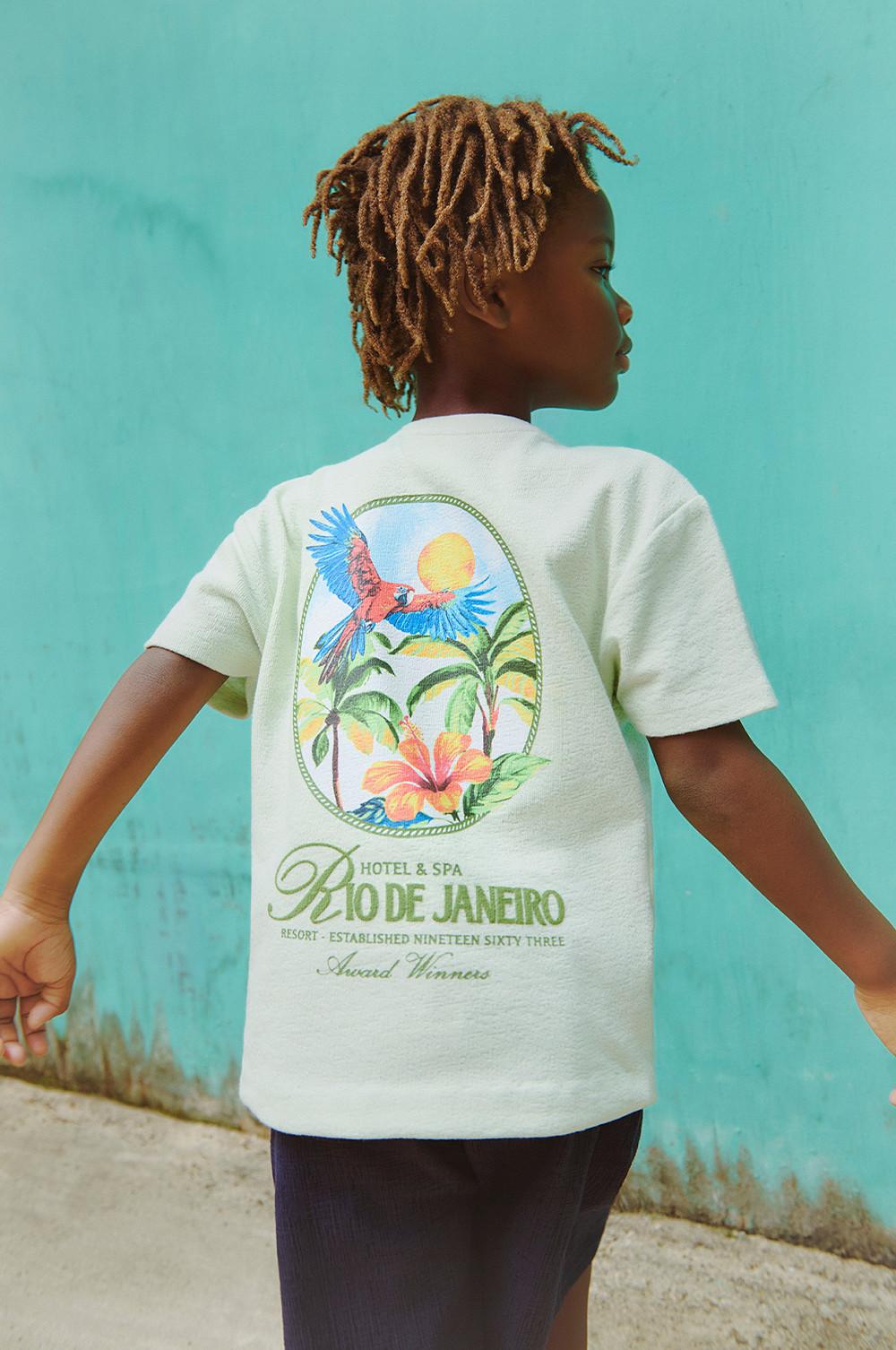 Light green T-shirt featuring tropical design with parrot, palm trees and flower, with Rio de Janeiro Hotel & Spa text on back.