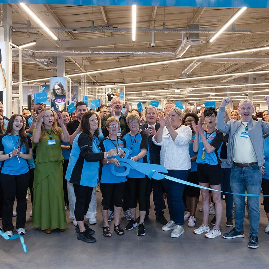 A group of people in a retail store celebrate a ribbon-cutting ceremony.