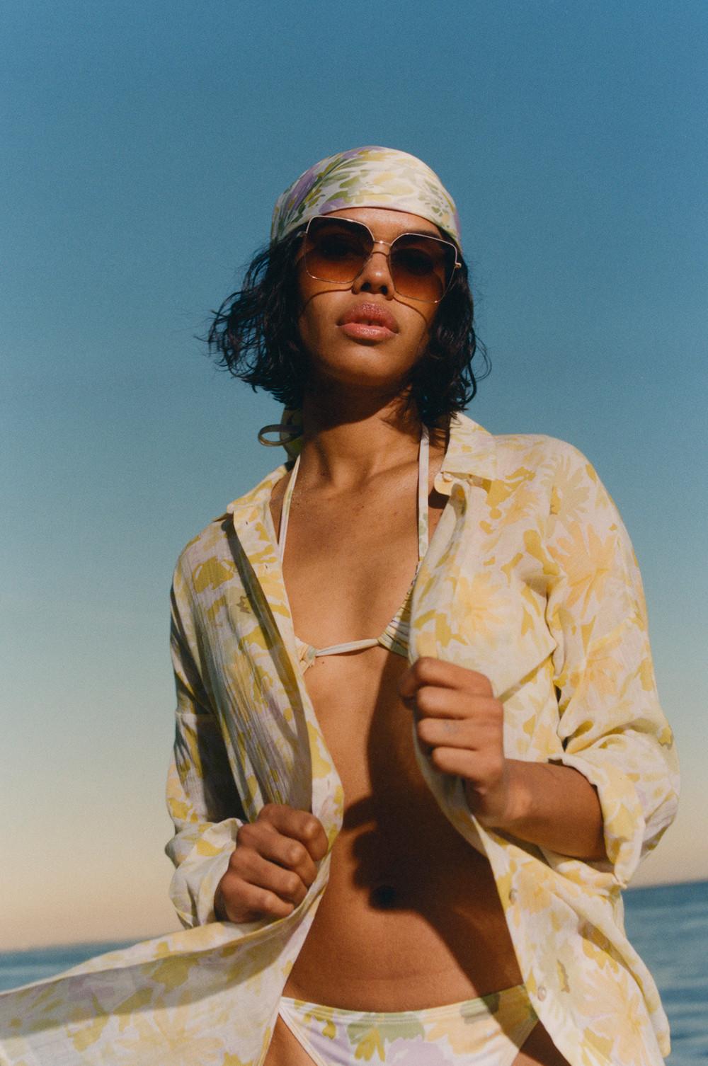 Model wears matching floral bikini, overshirt and headscarf