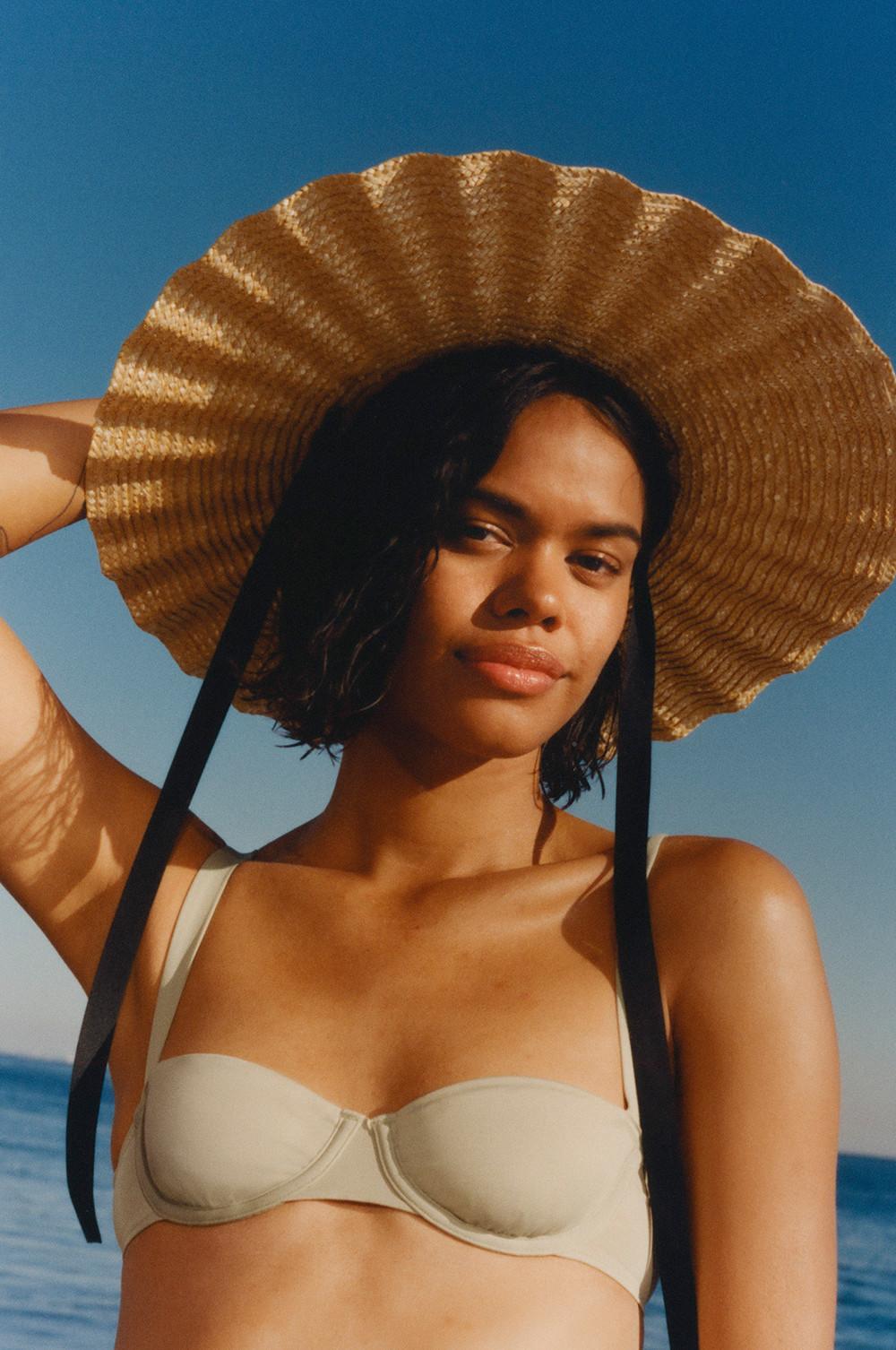 Model wears sage green underwired bikini and straw hat