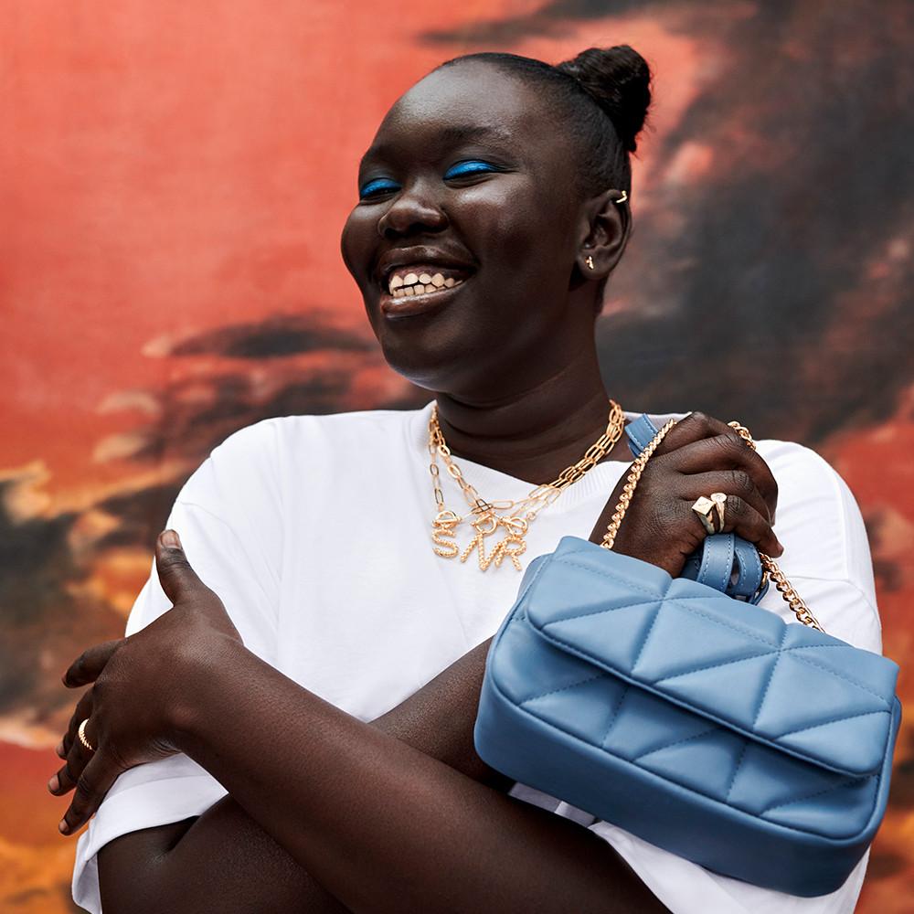 Model wearing white top and blue handbag