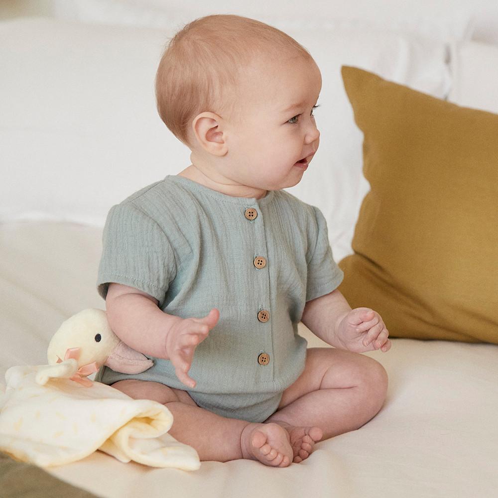 Baby draagt een groene romper met knoopjes