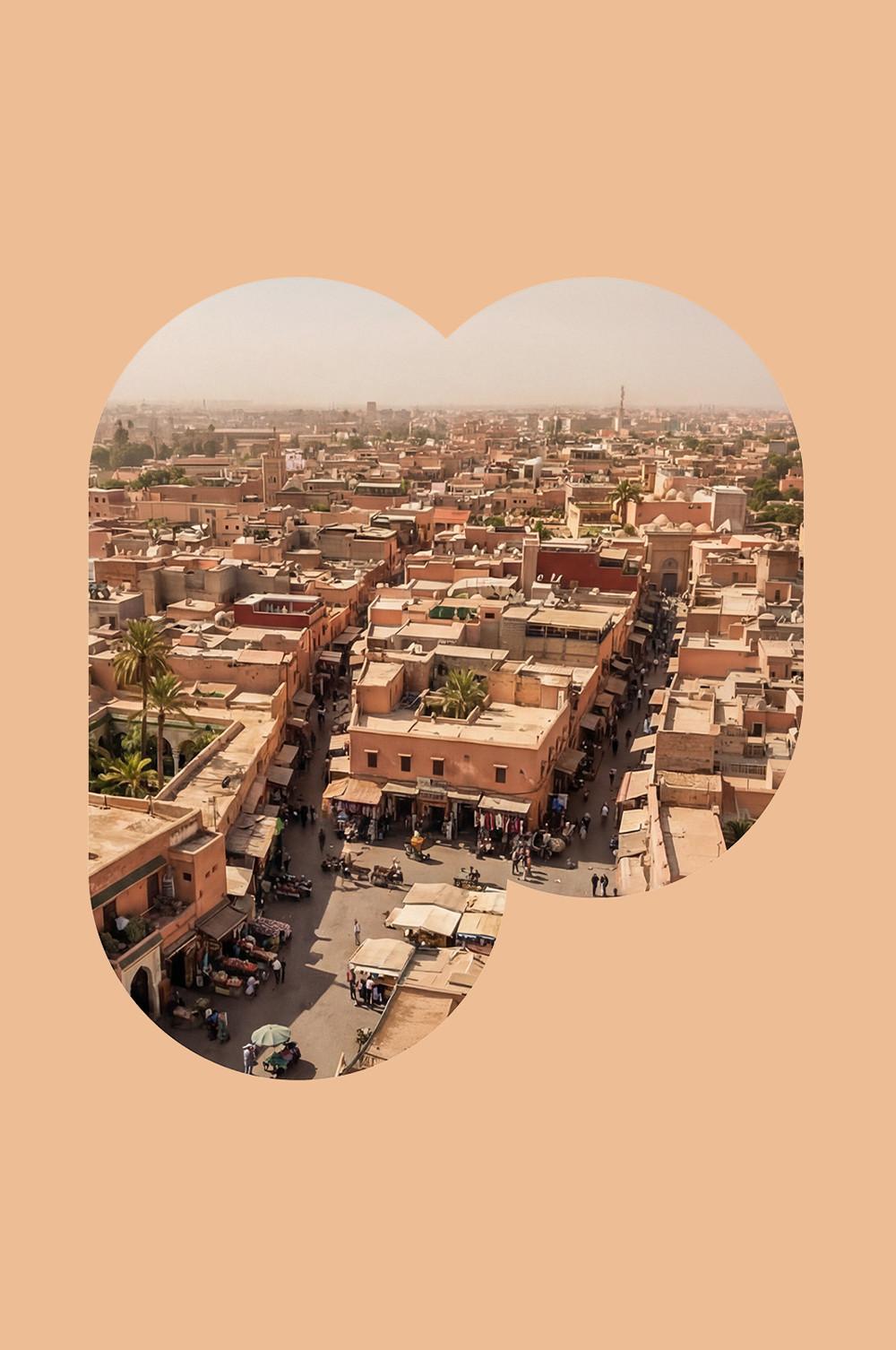 Vue aérienne d’un marché marocain animé, entouré de bâtiments en terre cuite et de palmiers, le tout dans un cadre en forme de cœur.