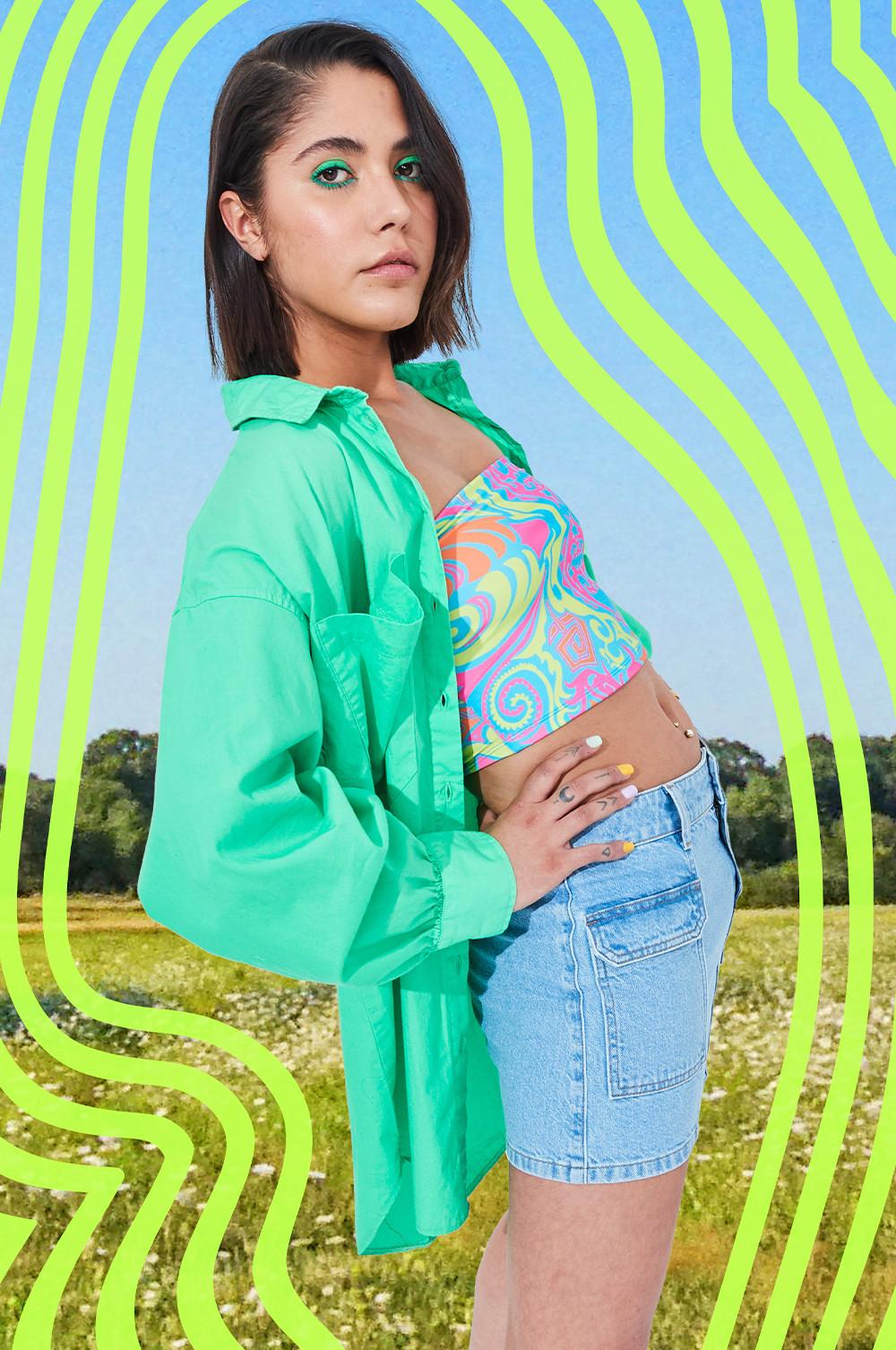 Model draagt denim minirok, strapless top met print en groene popeline overhemd