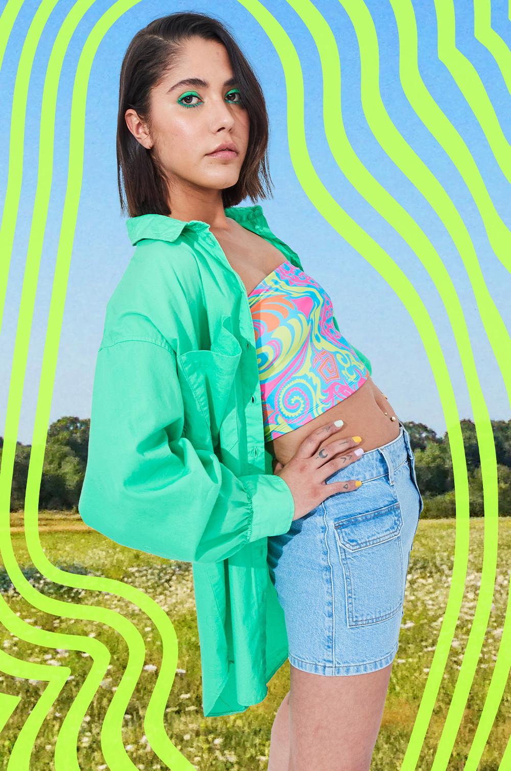 Model wears denim mini skirt, patterned bandeau top with a green poplin overshirt