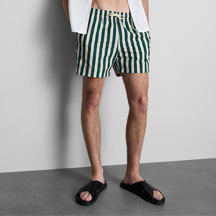 Green and white vertical striped shorts worn with a white shirt and black sandals.
