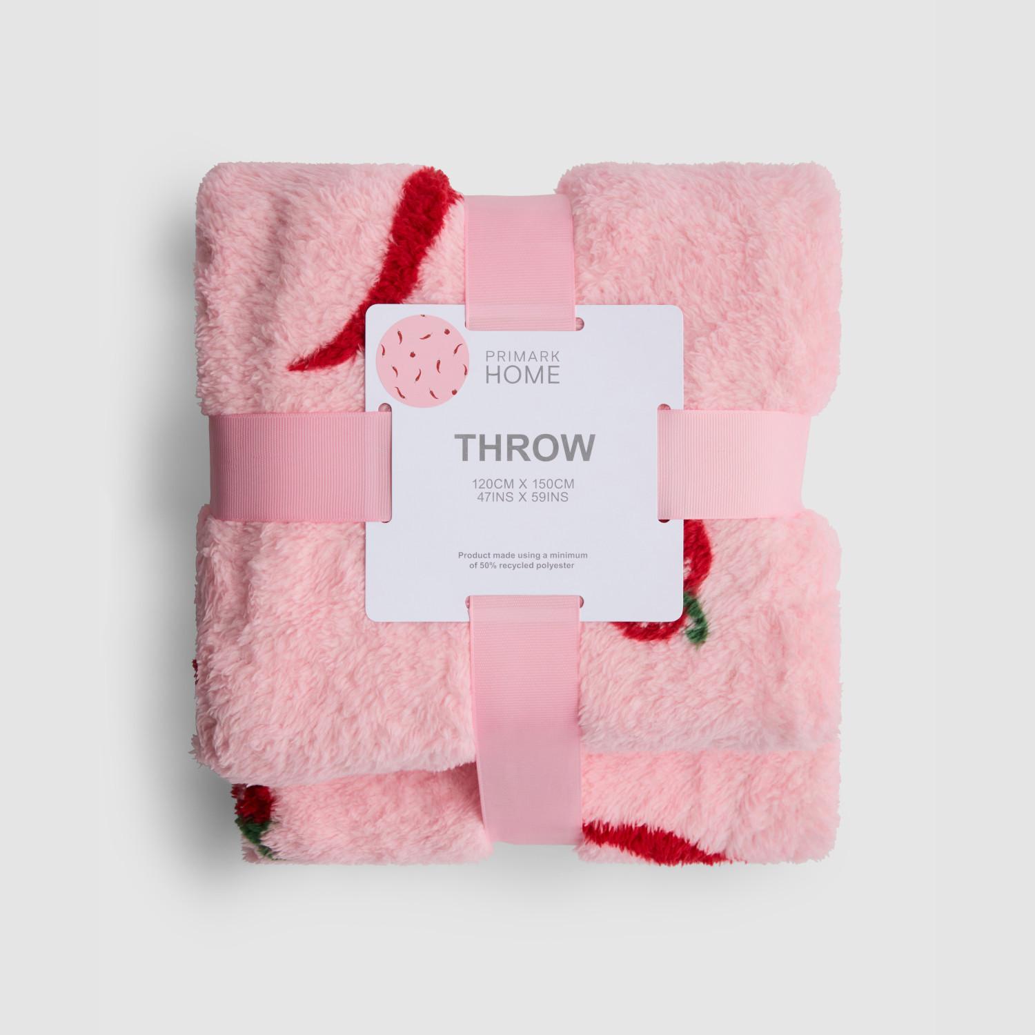 Primark Home pink fluffy throw with red and green floral design, secured with pink ribbon.