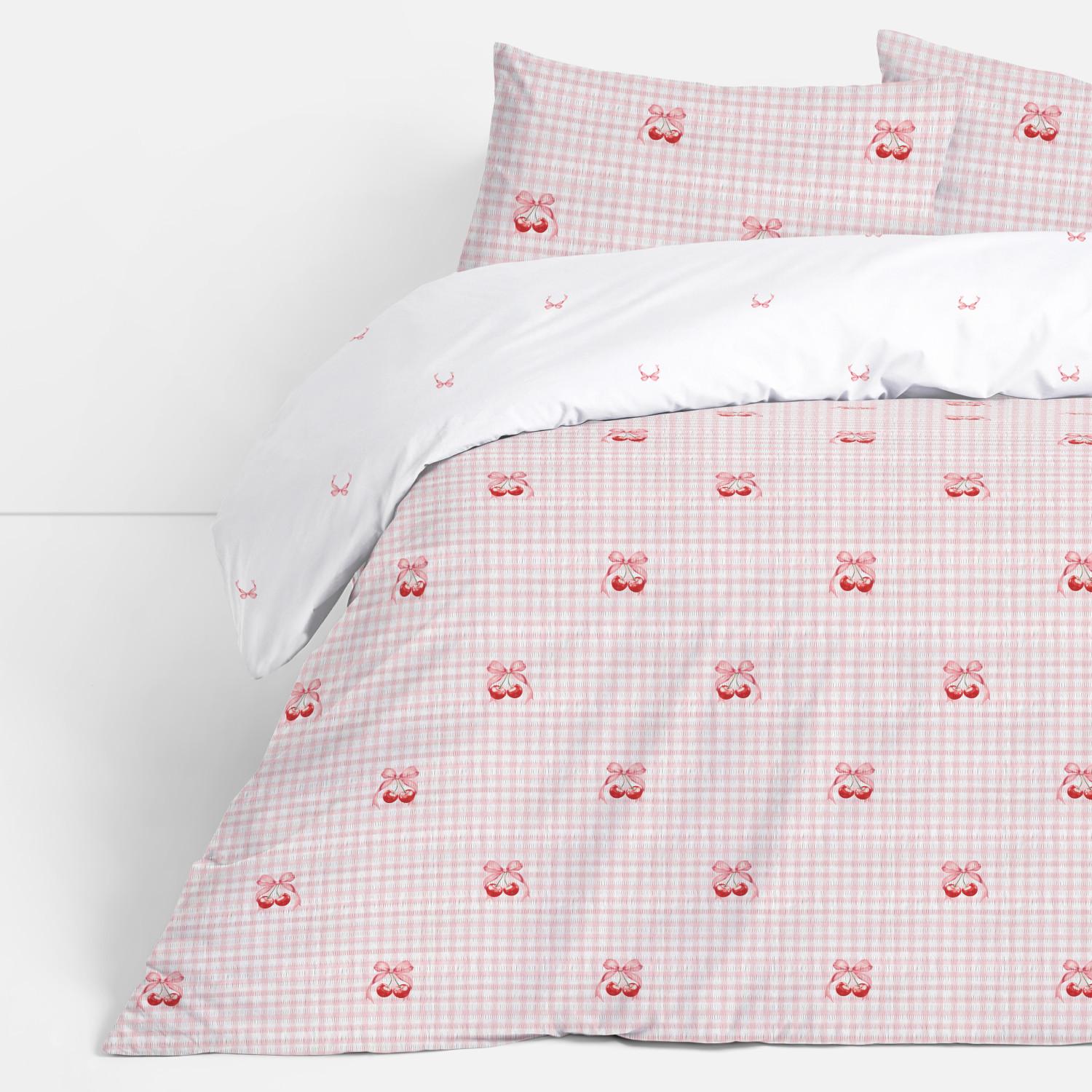 Pink gingham bedding set with cherry motif duvet cover and white sheet with small cherry print detail.