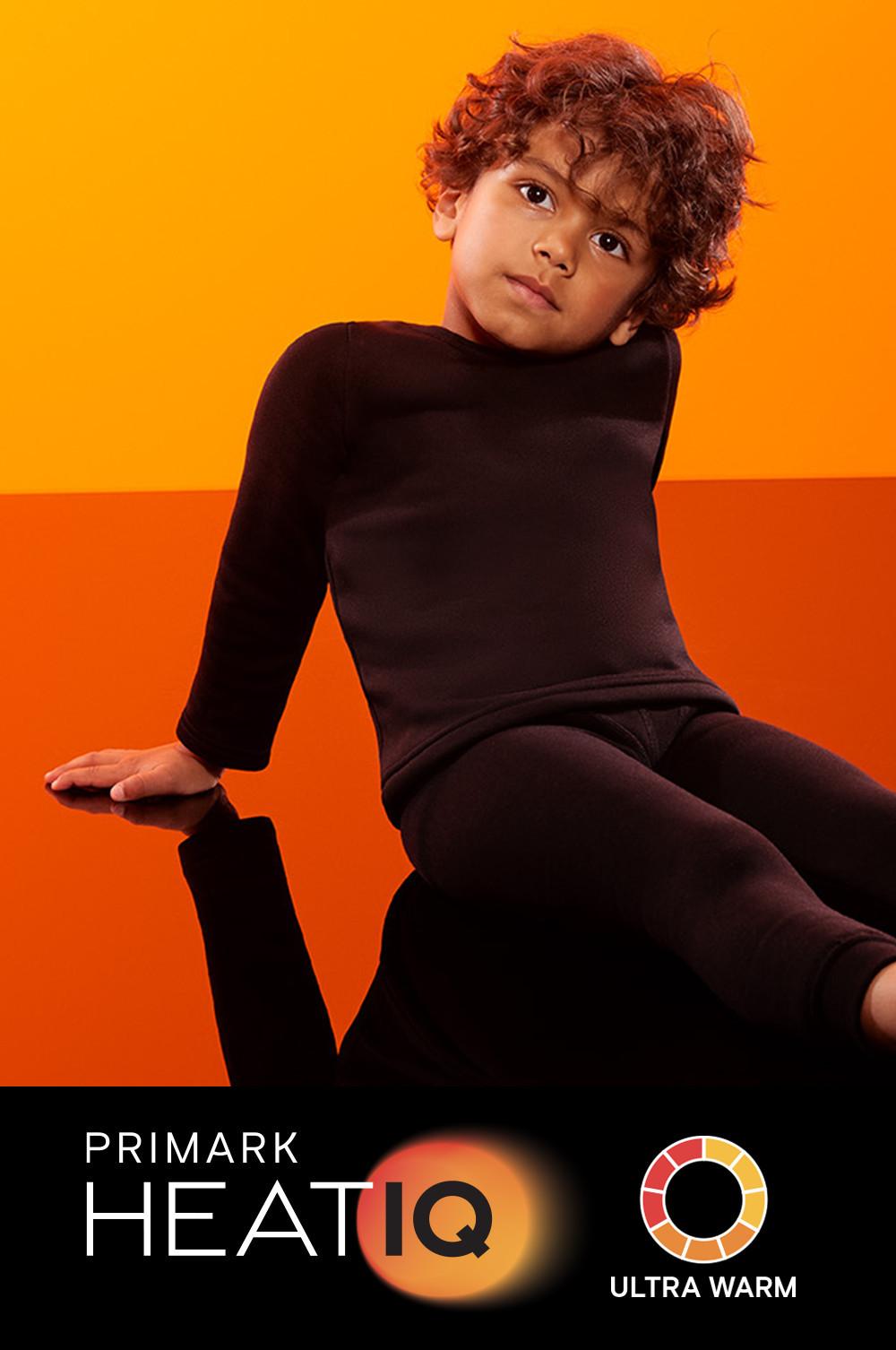 Child wearing brown Primark HEATIQ thermal loungewear set against an orange backdrop.