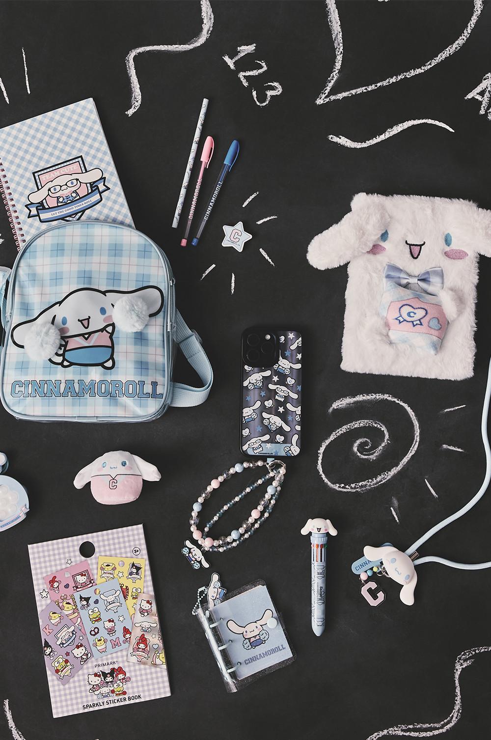 Collezione di cancelleria a tema Cinnamoroll con borsa in peluche, quaderno, custodia per smartphone e accessori su sfondo nero.