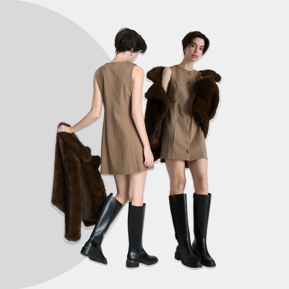 Models wearing brown pinstriped sleeveless dresses with fur coats and black knee-high boots.