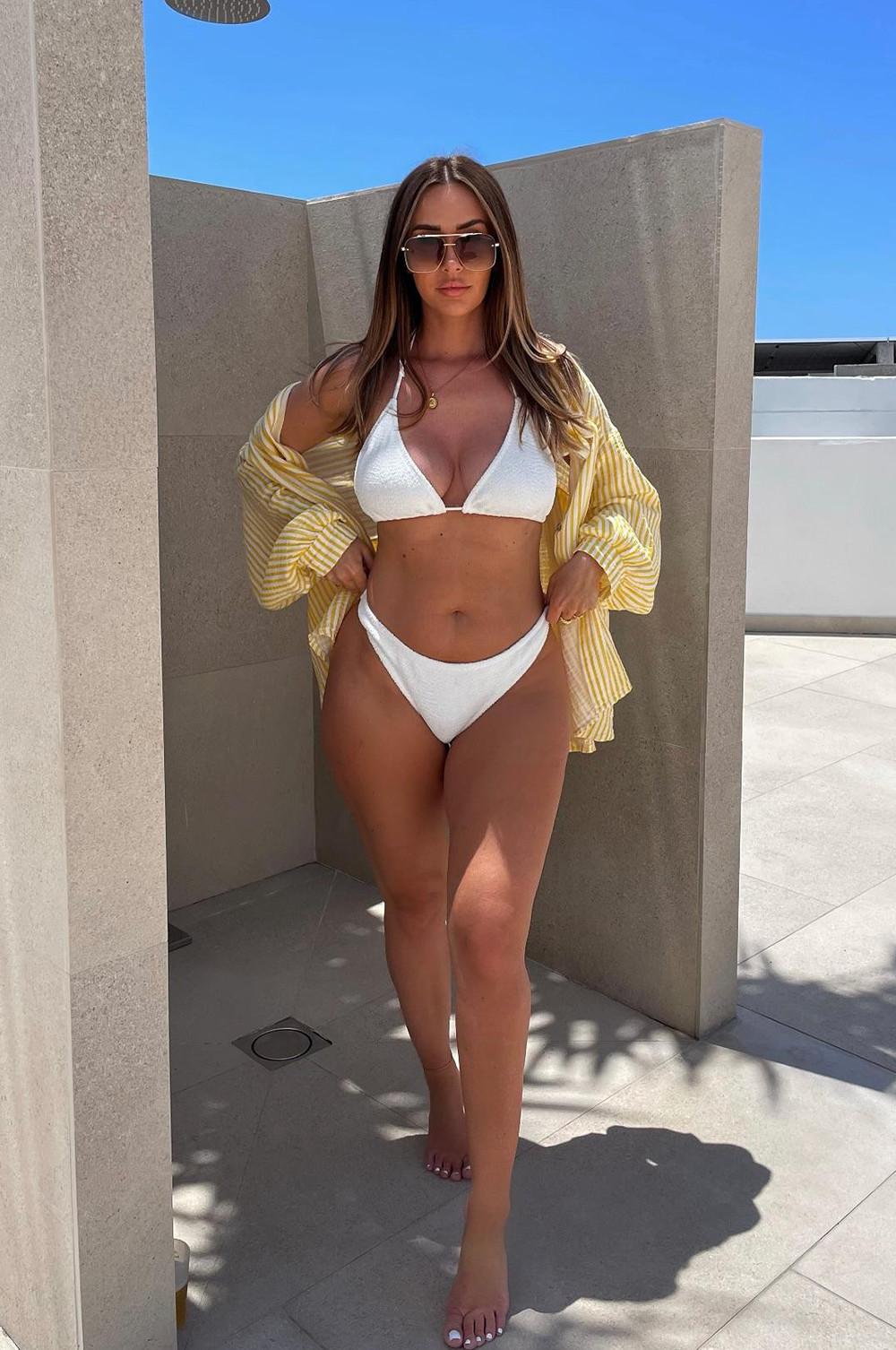 White triangle bikini with yellow striped shirt worn open as a cover-up and sunglasses