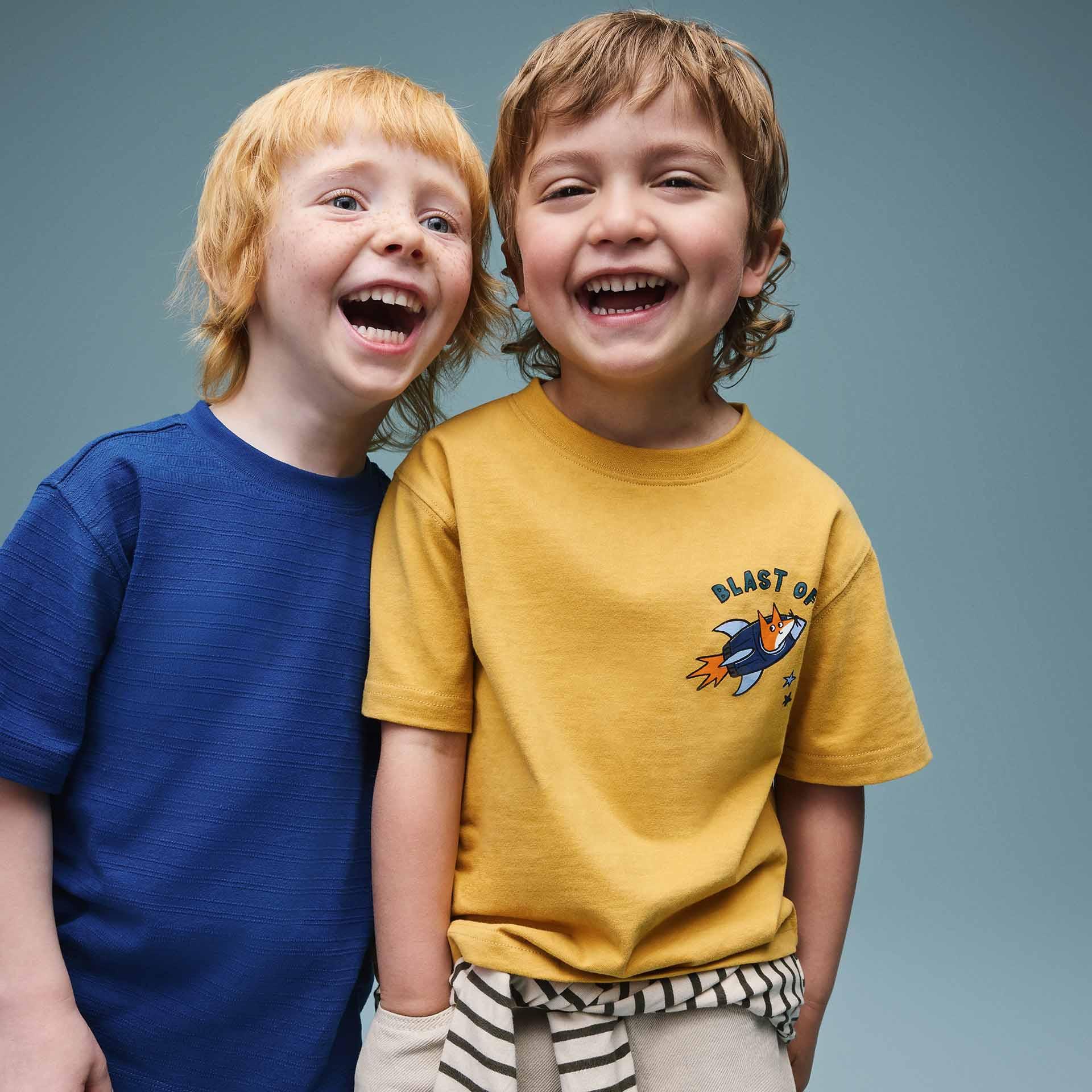 Two young boys laughing together, one wearing a blue t-shirt and the other a yellow t-shirt.