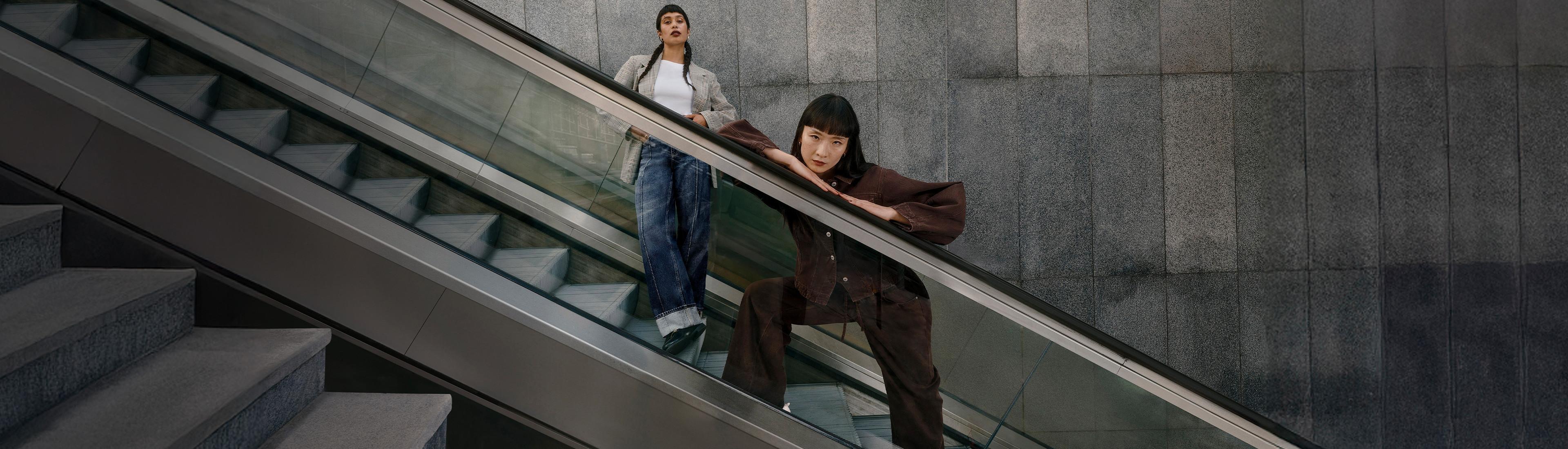 Two female models modelling Primark Denim on an escalator.