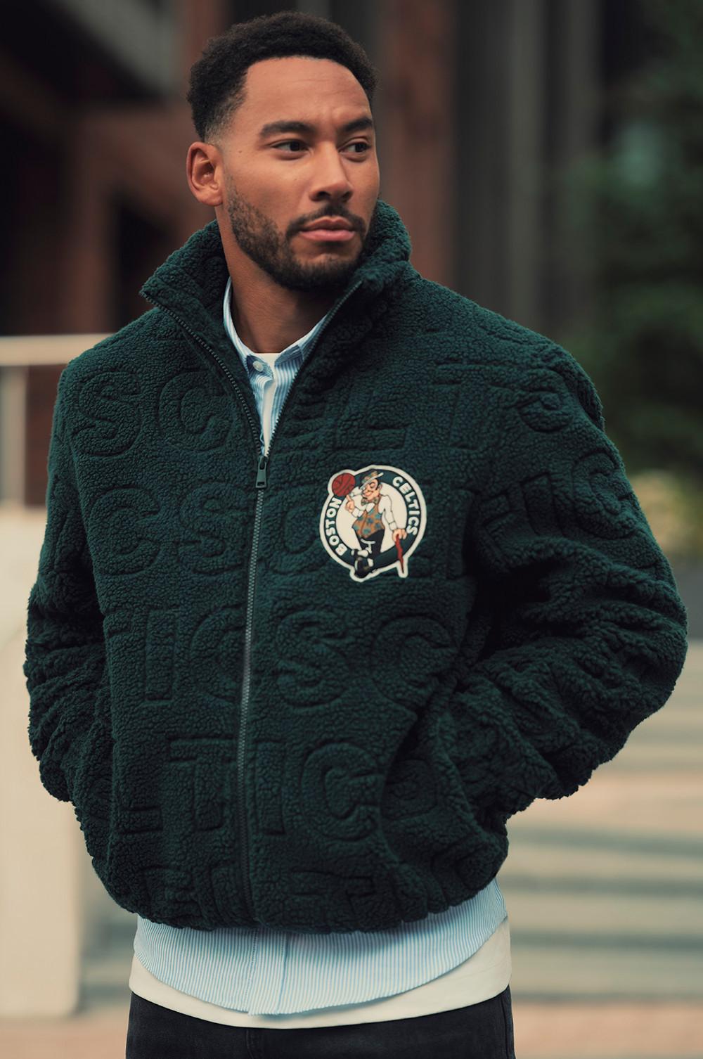 Chaqueta de forro polar texturizado de color verde oscuro con el logotipo de los Boston Celtics sobre una camisa de color azul claro.