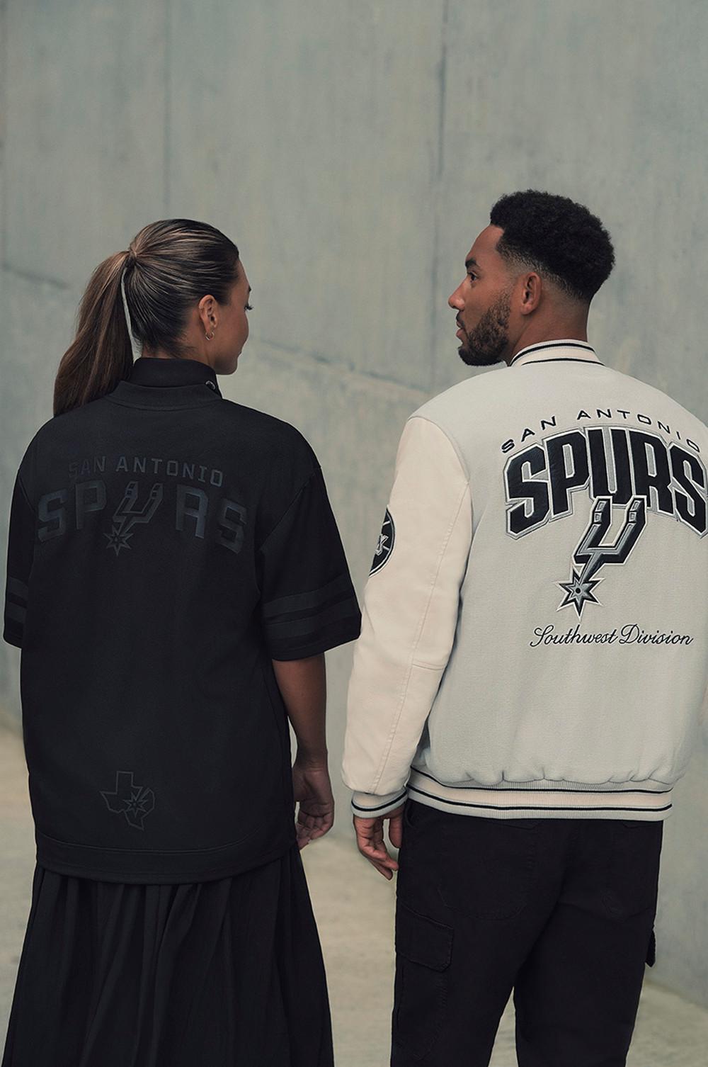 Dos modelos con prendas de los San Antonio Spurs: un jersey negro y una chaqueta blanca con el logotipo del equipo.