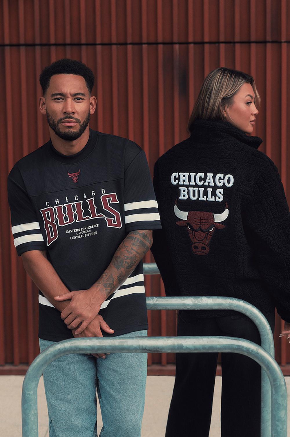 Dos modelos con prendas de los Chicago Bulls: una camiseta negra y un jersey negro con el logotipo del equipo.