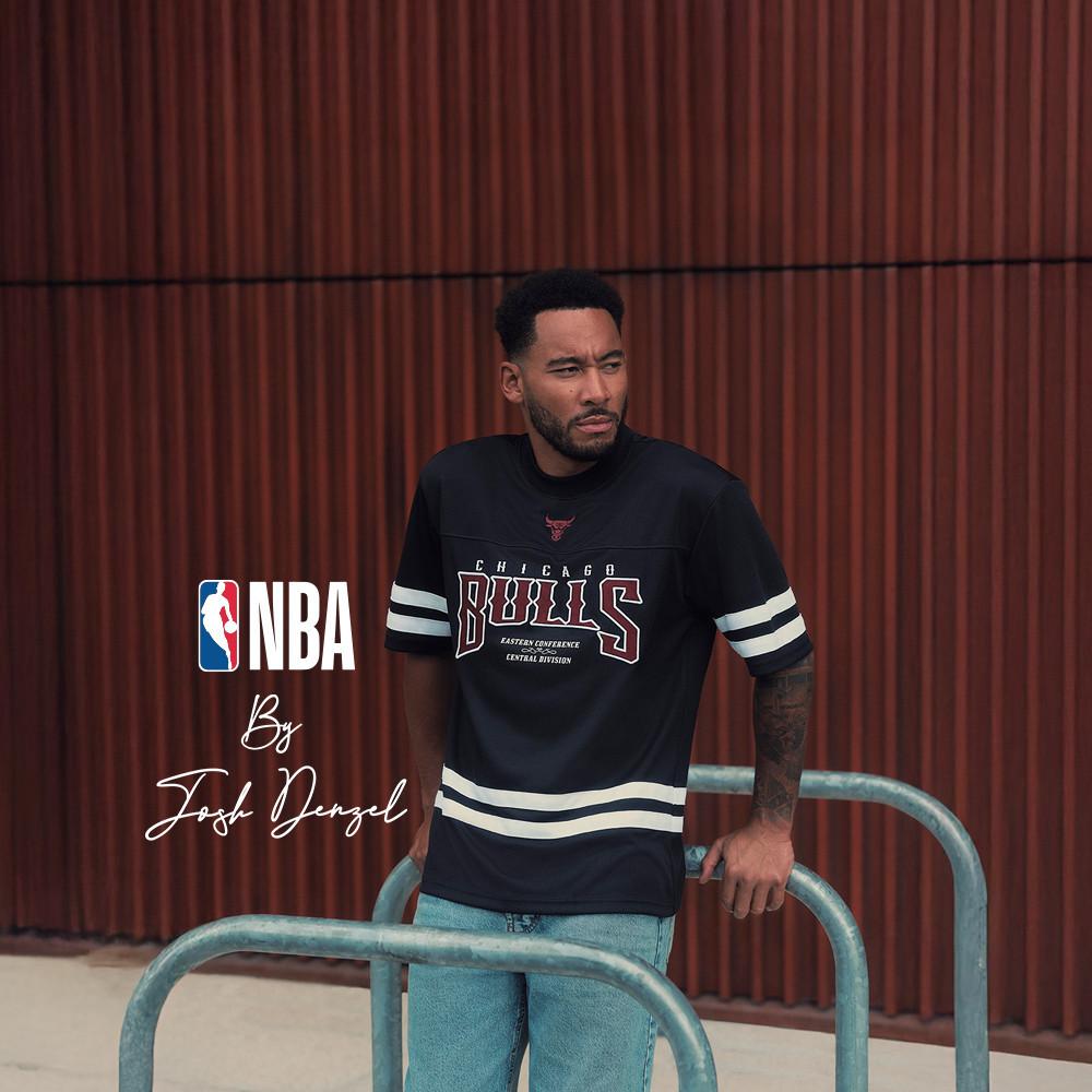 Modelo posando delante de una pared roja con un jersey negro de los Chicago Bulls de la NBA con rayas blancas.