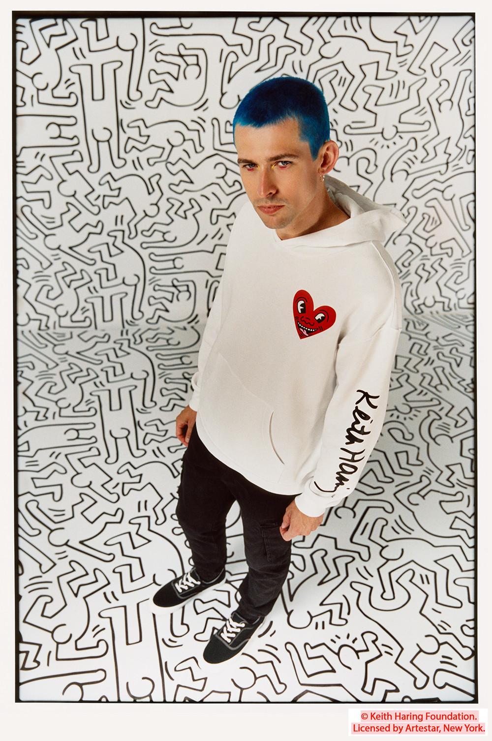 Das Model trägt weißen Keith Haring Kapuzenpullover mit Herzmotiv